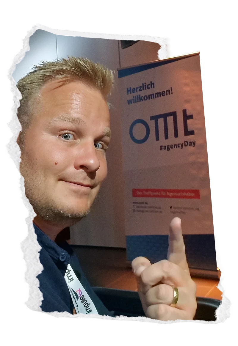 Mann mit Firmenbanner „Herzlich willkommen! OTTO agencyday“ und Handzeichen am Eventstand